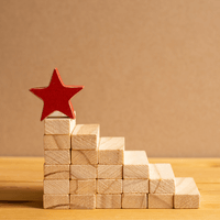 Photo shows the building blocks that look like stairs that reach toward a star at the top, representing how the steps to build a great compensation philosophy are chosen carefully and thoughtfully.